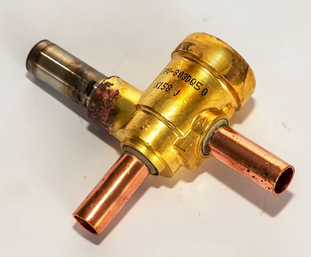 Magnetischer Ventilkörper von Daikin mit zwei Kupferanschlüssen, einem silbernen und einem goldfarbenen Teil, zur Verwendung in Heizsystemen.